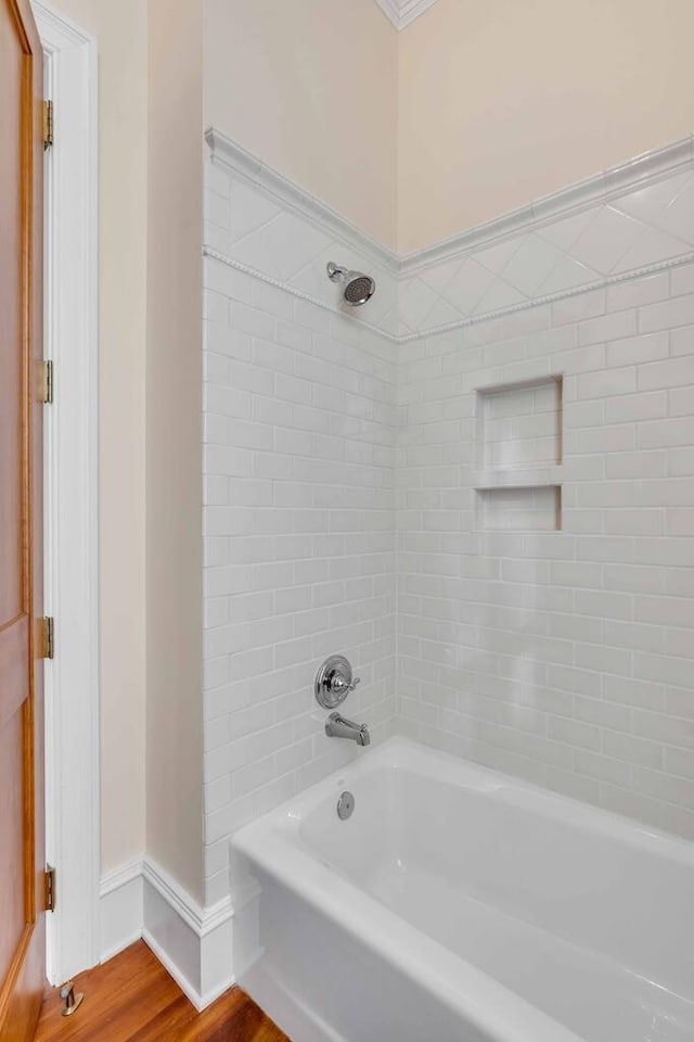 bathroom featuring shower / washtub combination, baseboards, and wood finished floors