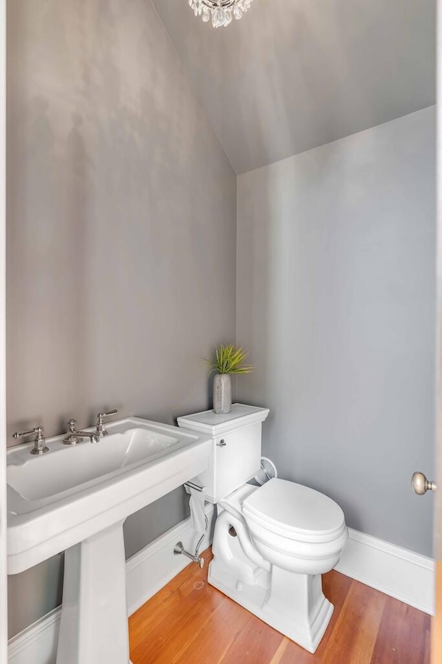 half bath with baseboards, toilet, and wood finished floors