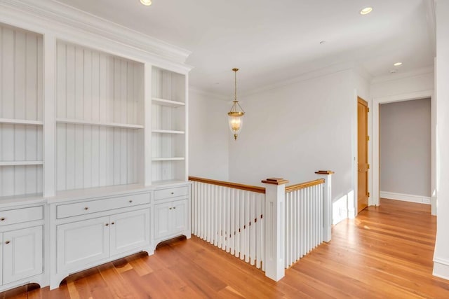 hallway featuring light wood-style floors, recessed lighting, ornamental molding, and an upstairs landing