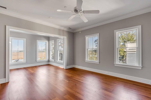 spare room with crown molding, plenty of natural light, and wood finished floors