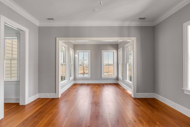 spare room featuring ornamental molding, wood finished floors, visible vents, and baseboards