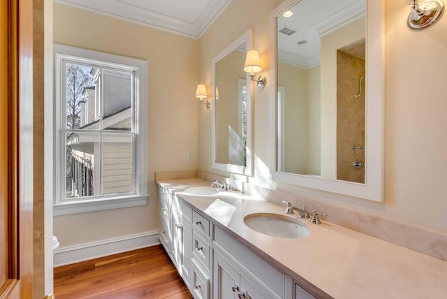 bathroom featuring double vanity, crown molding, a sink, and wood finished floors