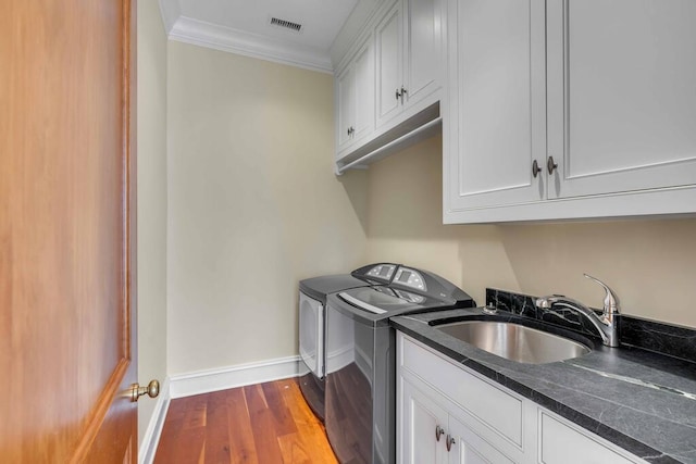 clothes washing area with cabinet space, baseboards, dark wood-style floors, separate washer and dryer, and a sink