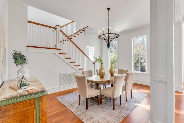 dining area featuring stairway, crown molding, visible vents, and wood finished floors