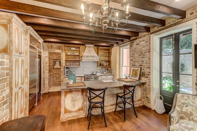 kitchen featuring premium range hood, brick wall, beamed ceiling, a breakfast bar area, and kitchen peninsula
