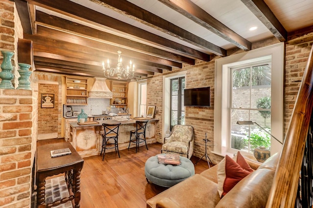 living room featuring brick wall, a healthy amount of sunlight, and an inviting chandelier