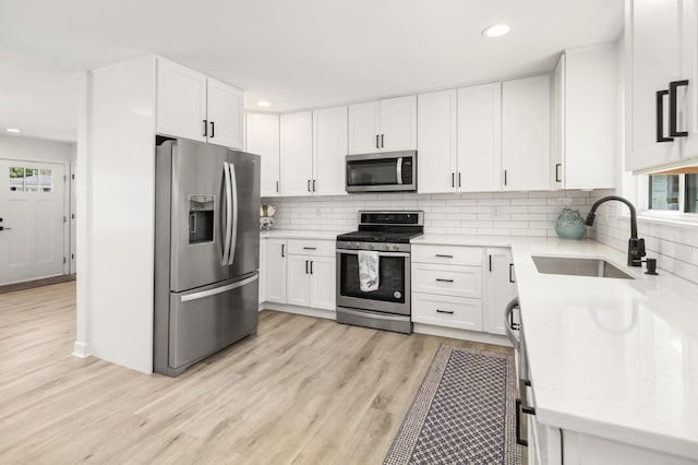 2137 Barbour Dr, Charleston, SC 29414 - kitchen with a sink, decorative backsplash, stainless steel appliances, white cabinetry, and light wood-type flooring