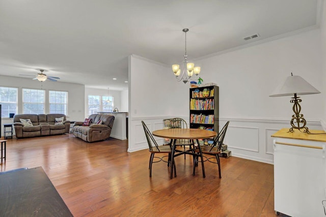 dining area featuring crown molding, wood-type flooring, and ceiling fan with notable chandelier