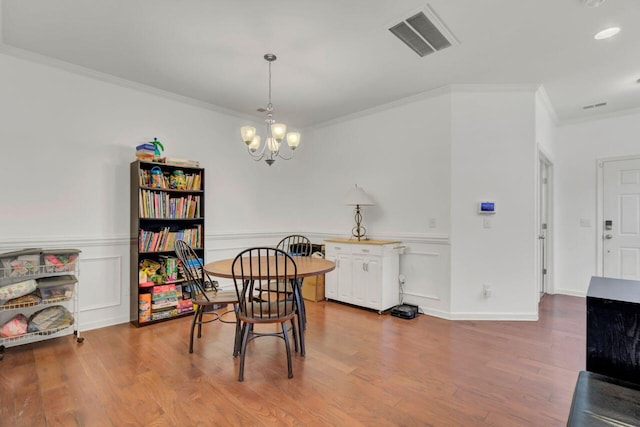 dining area featuring hardwood / wood-style floors, an inviting chandelier, and crown molding