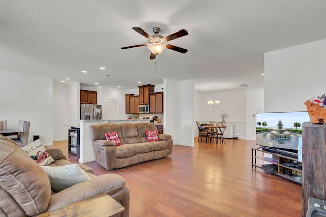 living room featuring ceiling fan with notable chandelier and light hardwood / wood-style floors