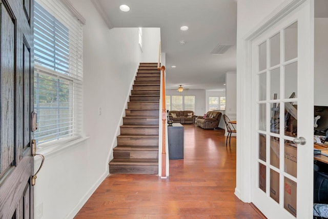 foyer entrance with hardwood / wood-style flooring, ceiling fan, crown molding, and french doors