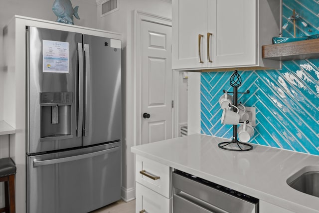 kitchen featuring stainless steel appliances, tasteful backsplash, light countertops, visible vents, and white cabinets