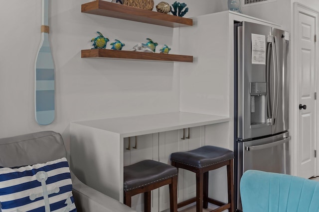 kitchen featuring a kitchen breakfast bar, visible vents, and stainless steel fridge with ice dispenser