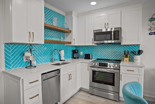 kitchen with stainless steel appliances, a sink, white cabinets, light countertops, and open shelves