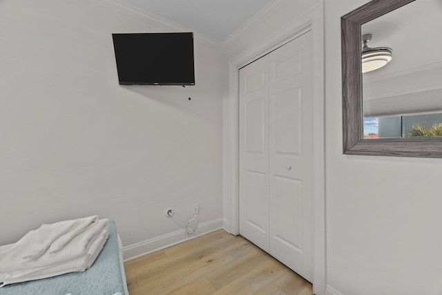 bedroom with light wood-style flooring, a closet, baseboards, and crown molding