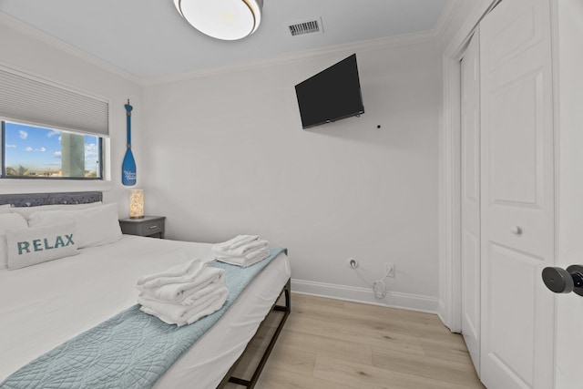 bedroom with light wood finished floors, baseboards, visible vents, and crown molding