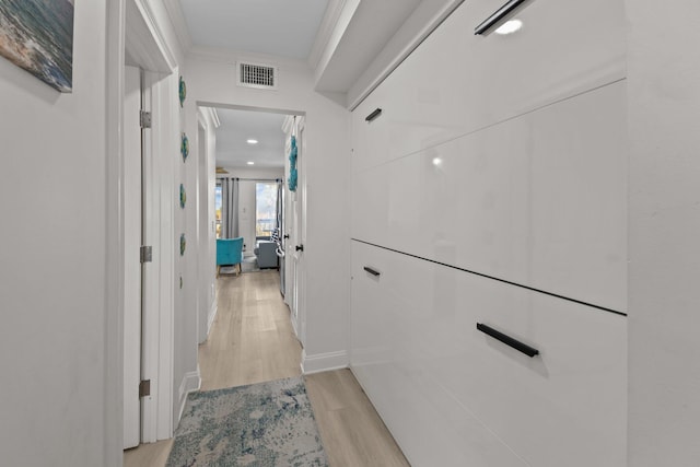 hall with ornamental molding, light wood-type flooring, and visible vents