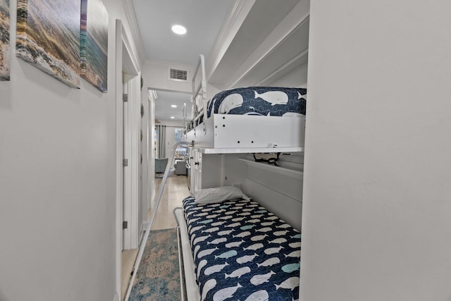 corridor with visible vents, wood finished floors, and ornamental molding