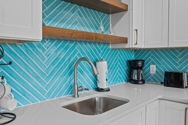 kitchen featuring white cabinetry, a sink, backsplash, and open shelves