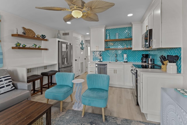 kitchen with stainless steel appliances, light countertops, white cabinetry, and a sink