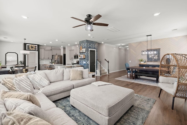 living room with ceiling fan with notable chandelier and dark hardwood / wood-style floors