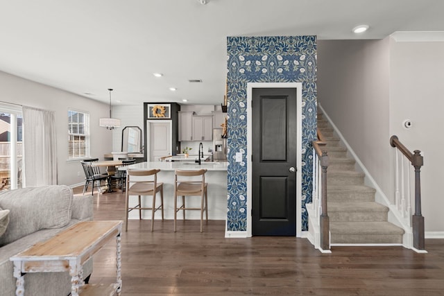 kitchen featuring gray cabinetry, sink, dark hardwood / wood-style floors, decorative light fixtures, and a kitchen bar