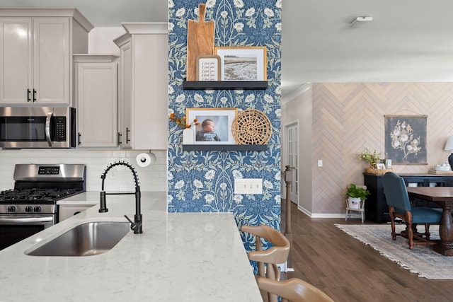 kitchen with sink, dark hardwood / wood-style floors, light stone countertops, appliances with stainless steel finishes, and tasteful backsplash