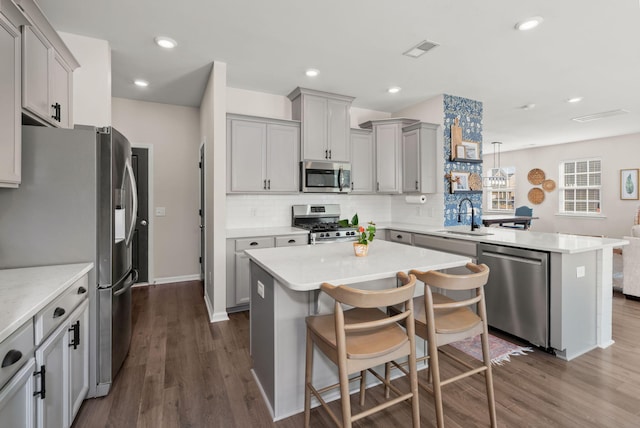 kitchen with dark hardwood / wood-style flooring, stainless steel appliances, sink, decorative light fixtures, and a kitchen island