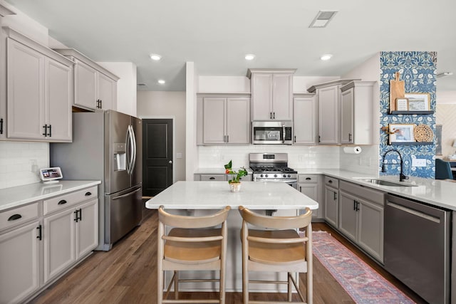 kitchen featuring sink, gray cabinets, appliances with stainless steel finishes, dark hardwood / wood-style flooring, and a breakfast bar area