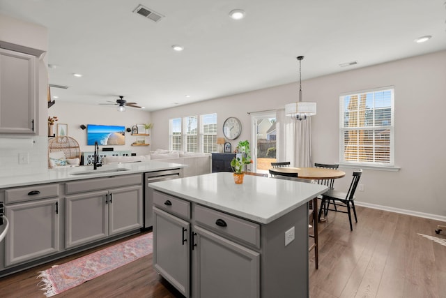 kitchen with pendant lighting, ceiling fan with notable chandelier, gray cabinetry, and sink