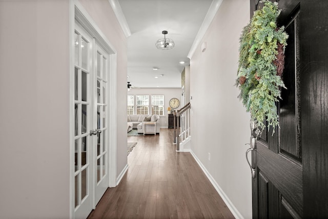 hall with a notable chandelier, dark hardwood / wood-style flooring, french doors, and ornamental molding