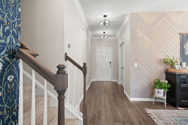 foyer featuring hardwood / wood-style flooring, crown molding, and a notable chandelier