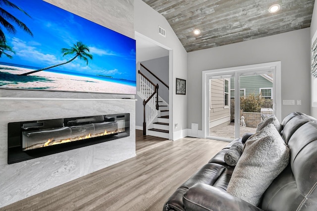 living room featuring visible vents, lofted ceiling, wood finished floors, stairs, and a fireplace