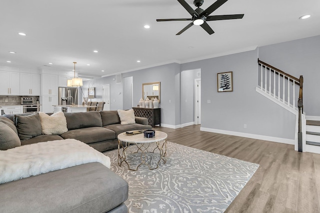 living area featuring light wood finished floors, stairway, and ornamental molding