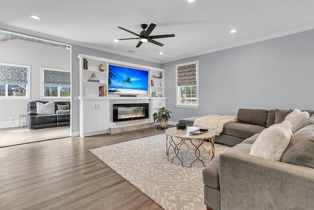 living room featuring ornamental molding, wood finished floors, a glass covered fireplace, and recessed lighting