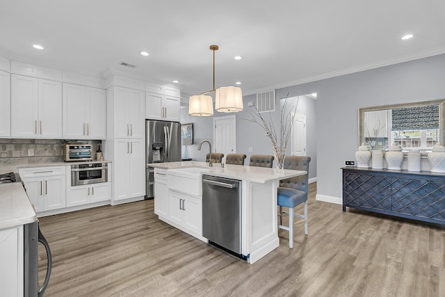 kitchen with light wood-type flooring, appliances with stainless steel finishes, light countertops, and a sink