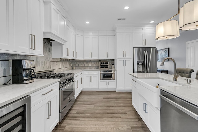 kitchen with tasteful backsplash, visible vents, wine cooler, appliances with stainless steel finishes, and a sink