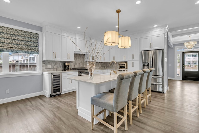 kitchen with wine cooler, stainless steel appliances, a sink, light countertops, and tasteful backsplash