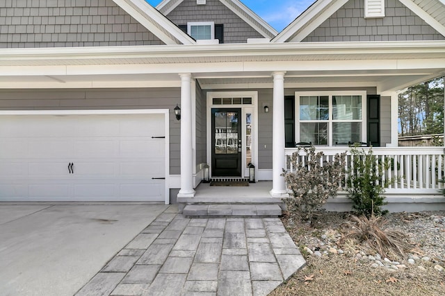 view of exterior entry featuring covered porch, driveway, and an attached garage