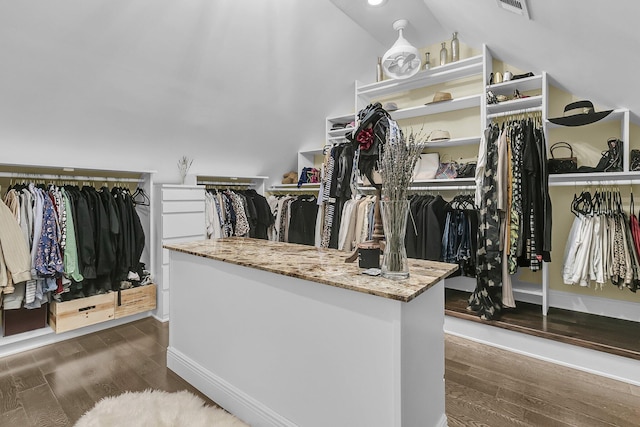 walk in closet with vaulted ceiling, visible vents, and dark wood finished floors