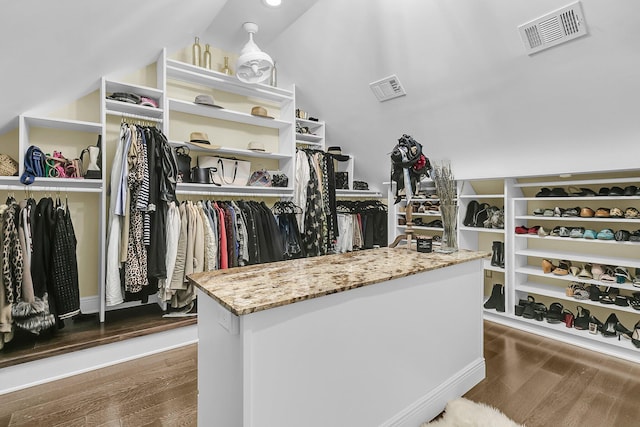 spacious closet with lofted ceiling, visible vents, and wood finished floors