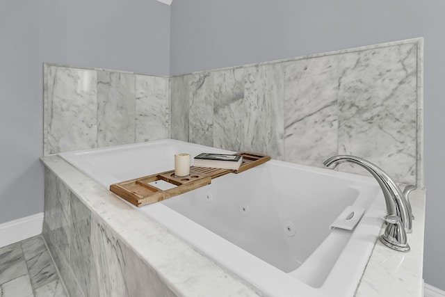 bathroom featuring marble finish floor, a jetted tub, and baseboards