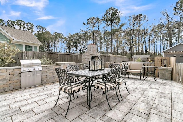 view of patio with a fenced backyard, a fireplace, and area for grilling