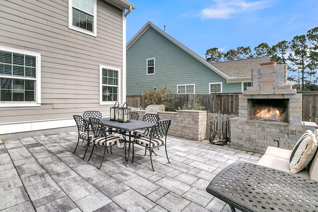 view of patio / terrace with an outdoor brick fireplace, an outdoor kitchen, grilling area, fence, and outdoor dining area