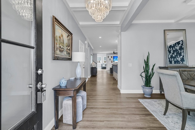 foyer entrance with baseboards, beamed ceiling, a notable chandelier, and wood finished floors