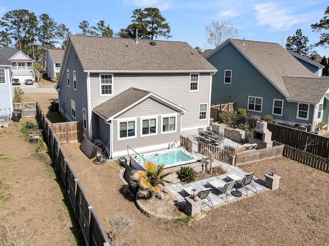 rear view of house featuring a fenced backyard, a shingled roof, and a patio