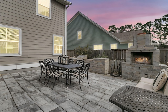 view of patio / terrace with an outdoor brick fireplace, a grill, fence, and outdoor dining space