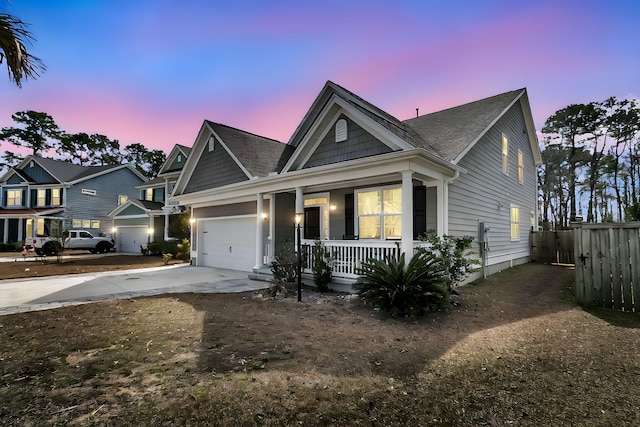 view of front of house featuring covered porch, driveway, an attached garage, and fence