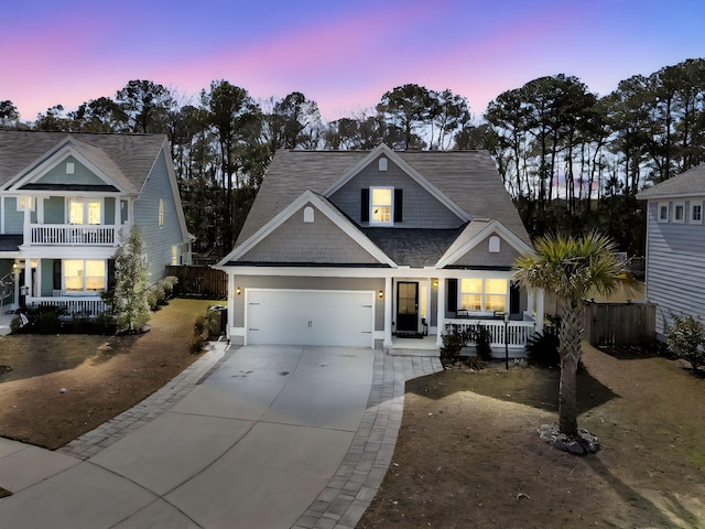 view of front facade featuring a garage, covered porch, driveway, and fence