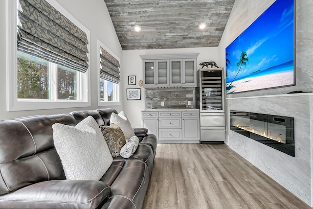 living area featuring beverage cooler, a glass covered fireplace, and light wood-style flooring